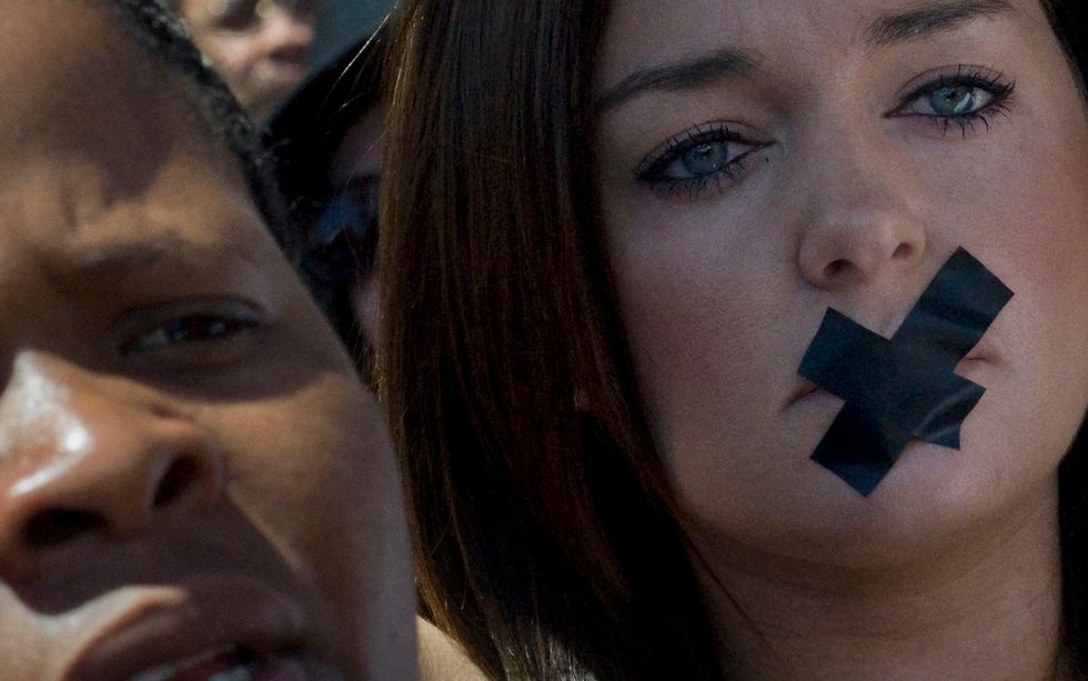 A woman with tape over her mouth. (Photo: RODGER BOSCH/AFP/Getty Images)