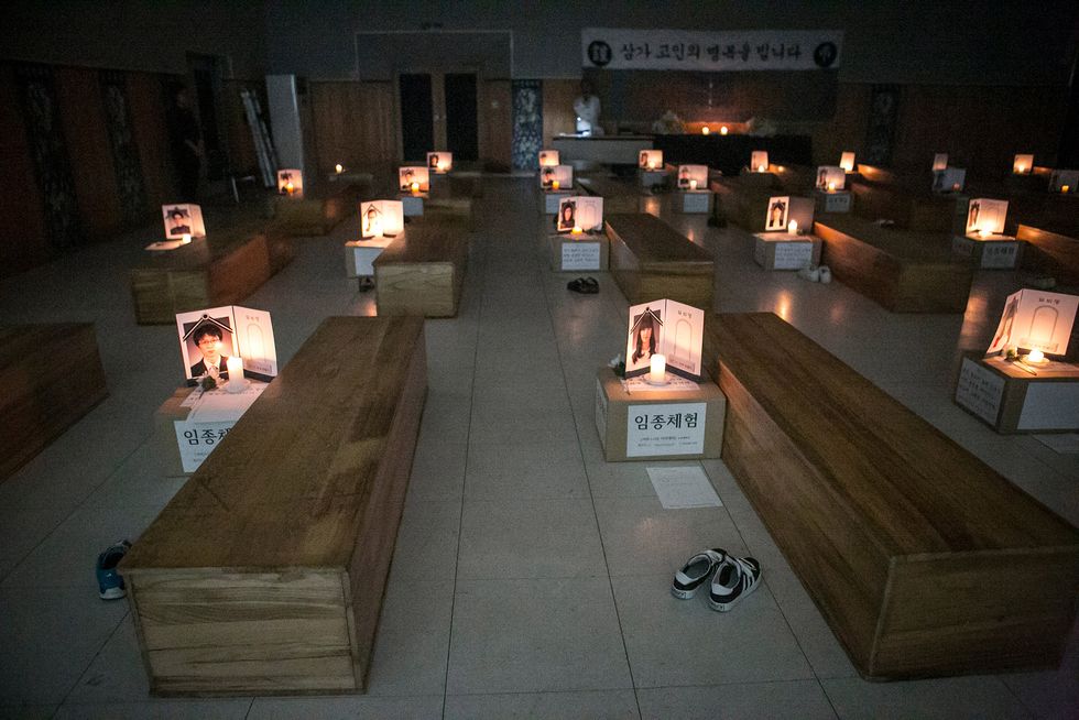 Participants think about their lives as they lie down in a coffin during a 'Death Experience/Fake Funeral' session held by Happy Dying on August 1, 2016 in Andong, South Korea. Fifty adults who work at the Andong Science College in South Korea participate