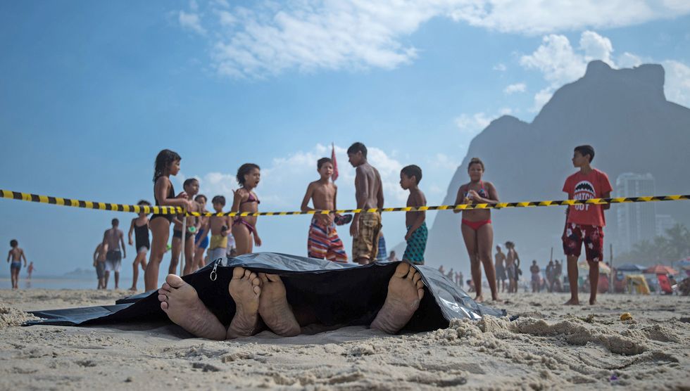 People remain at the beach near two corpses after the collapse of a bicycle track in Rio de Janeiro, Brazil. (Photo: CHRISTOPHE SIMON/AFP/Getty Images)