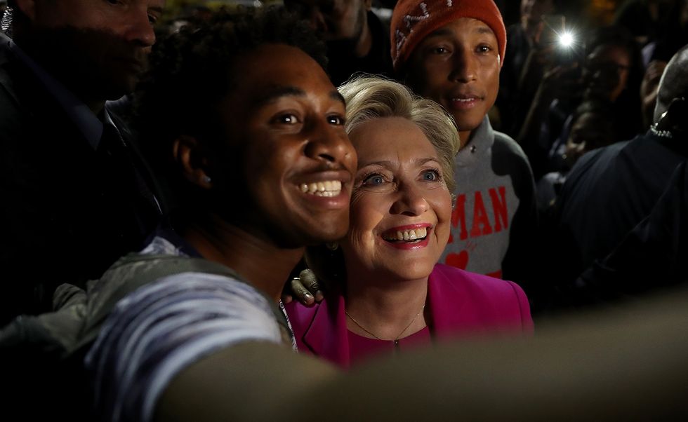 Democratic presidential nominee Hillary Clinton (C) and recording artist Pharrell Williams (R) take a selfie with a student at North Carolina Central University on November 3, 2016 in Durham, North Carolina. (Photo by Justin Sullivan/Getty Images)