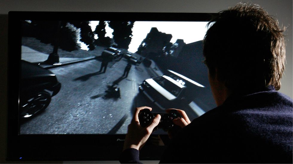 A young man plays Grand Theft Auto IV
