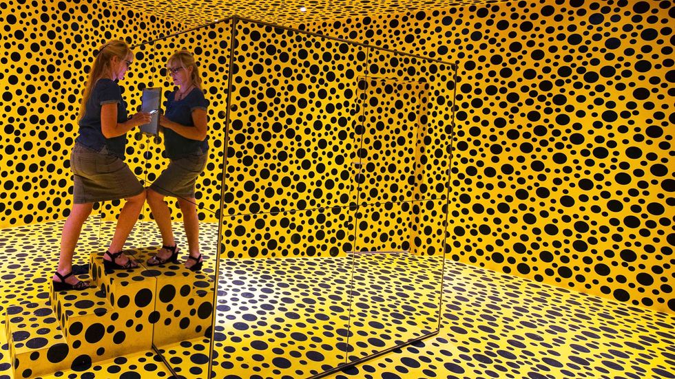 A visitor checks an art installation entitled 'Mirror Room (Pumpkin)' by Japanese artist Yayoi Kusama, part of the In Infinity art exhibition at the Moderna Museet, the Museum of Modern Art on August 31, 2016, Stockholm. (JONATHAN NACKSTRAND/A