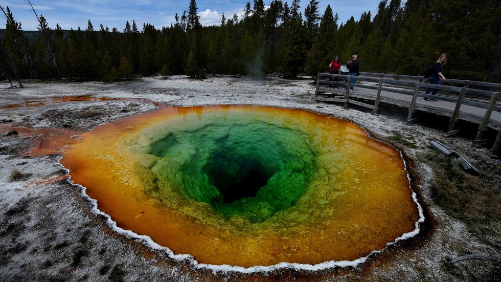 Tourists view the Morning Glory hot spring in the Upper Geyser Basin of Yellowstone National Park in Wyoming, on May 14, 2016. (Credit: MARK RALSTON/AFP/Getty Images)