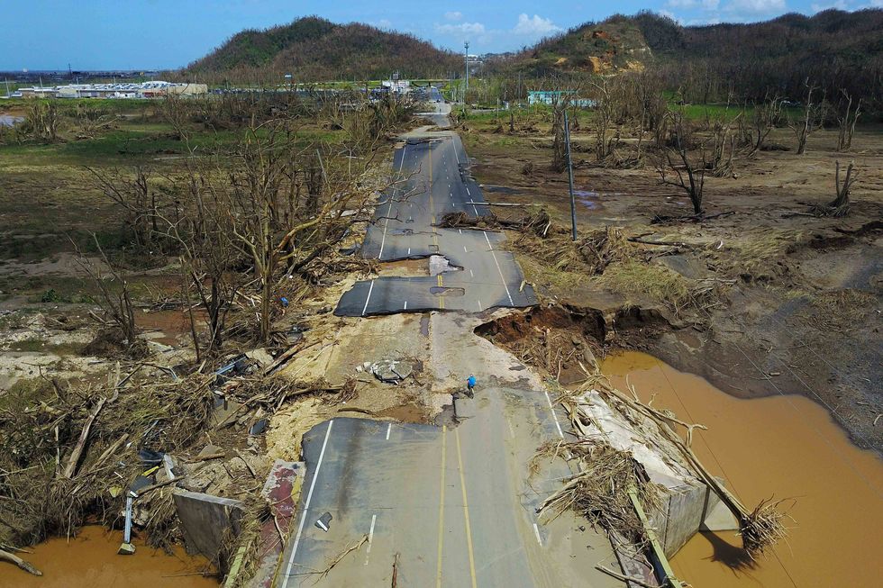 A man rides his bicycle through a damaged road in Toa Alta, west of San Juan, Puerto Rico, on September 24, 2017 following the passage of Hurricane Maria. RICARDO ARDUENGO/AFP/Getty Images)