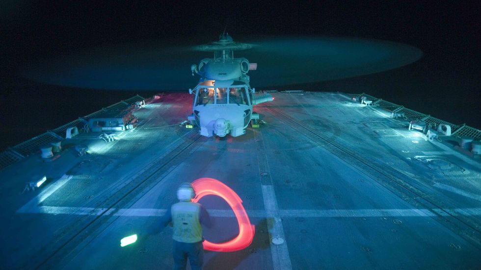 A Sailor directs an SH-60B Sea Hawk helicopter as it prepares to shut down after landing aboard the guided-missile destroyer USS Nitze DDG 94, Gulf Of Aden, 2012. (Smith Collection/Gado/Getty Images)
