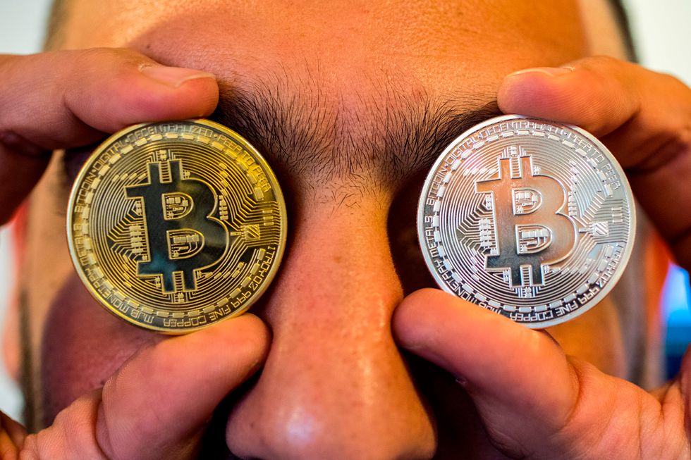 Man holding bitcoins over his eyes.