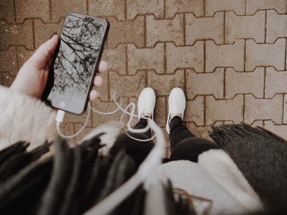 girl listening to music outside on iphone with headphones
