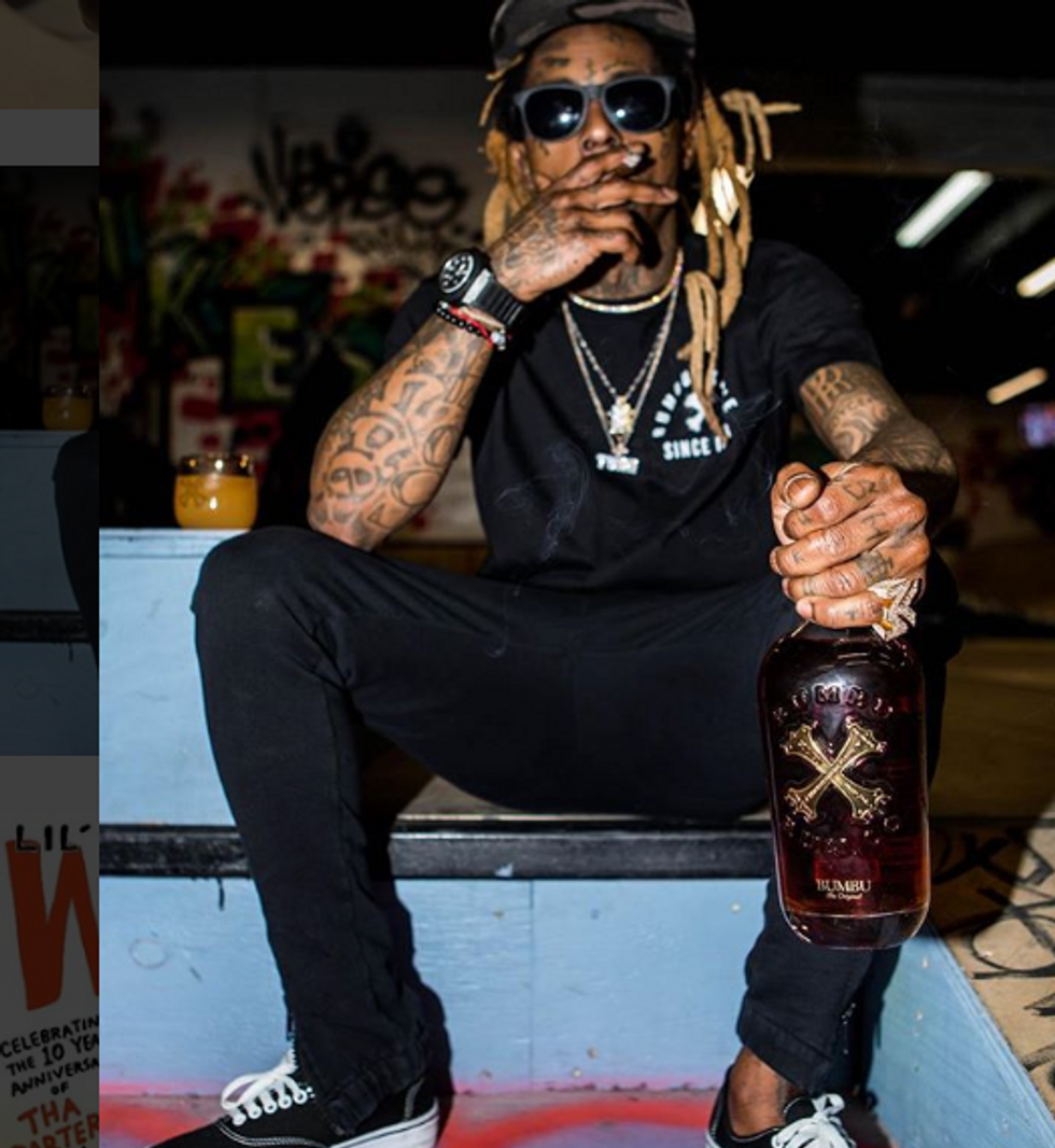 Lil Wayne holding a bottle of alcohol