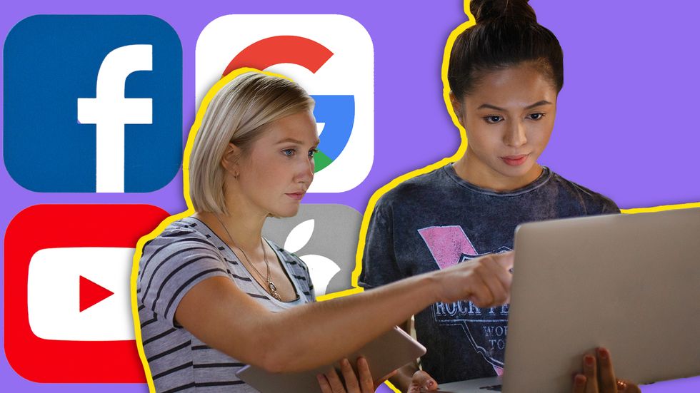 Two diverse women in tech discussing work in front of a laptop.