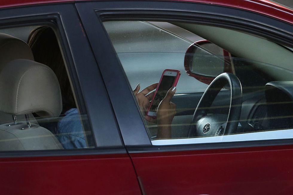 A driver uses a phone while behind the wheel of a car on April 30, 2016 in New York City. (Photo by Spencer Platt/Getty Images)