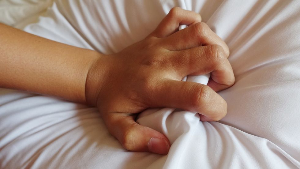 hand gripping the sheets in passion during sex / orgasm