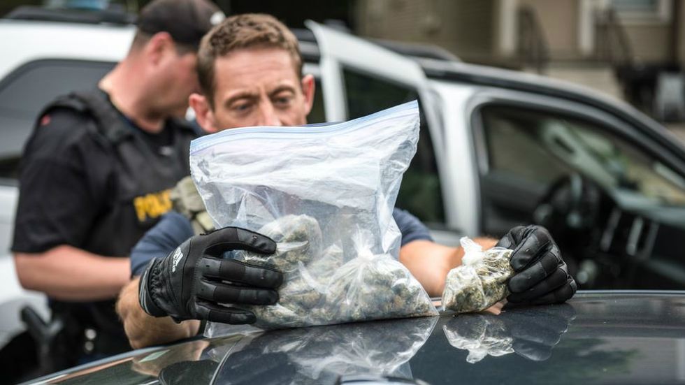 A police officer looking at a bad of marijuana