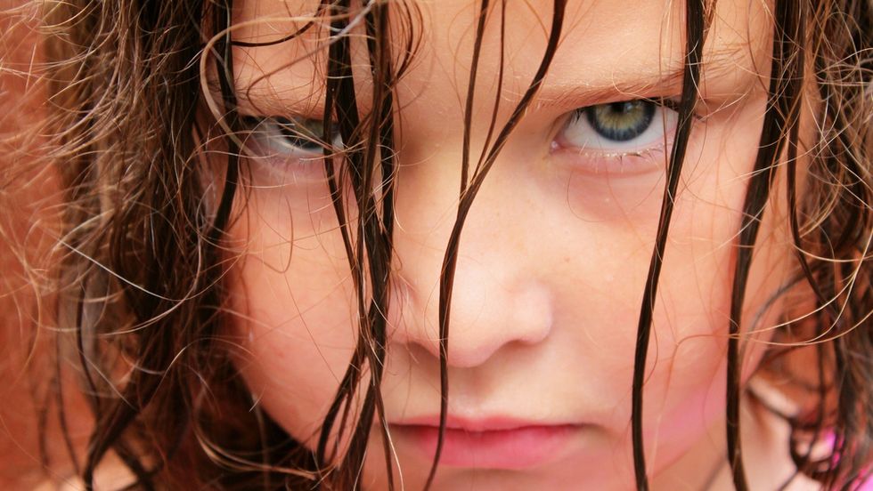 An angry kid young girl with glaring eyes stare