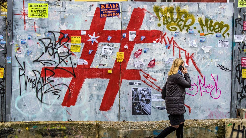 A woman speaks on a mobile phone as she walks past a graffiti covered wall with a giant hashtag sign near Moscow's Kursky railway station on November 17, 2017. (Photo: MLADEN ANTONOV/AFP/Getty Images)
