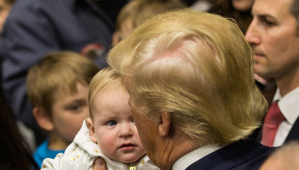 Donald Trump holds a baby, who is totally judging him.
