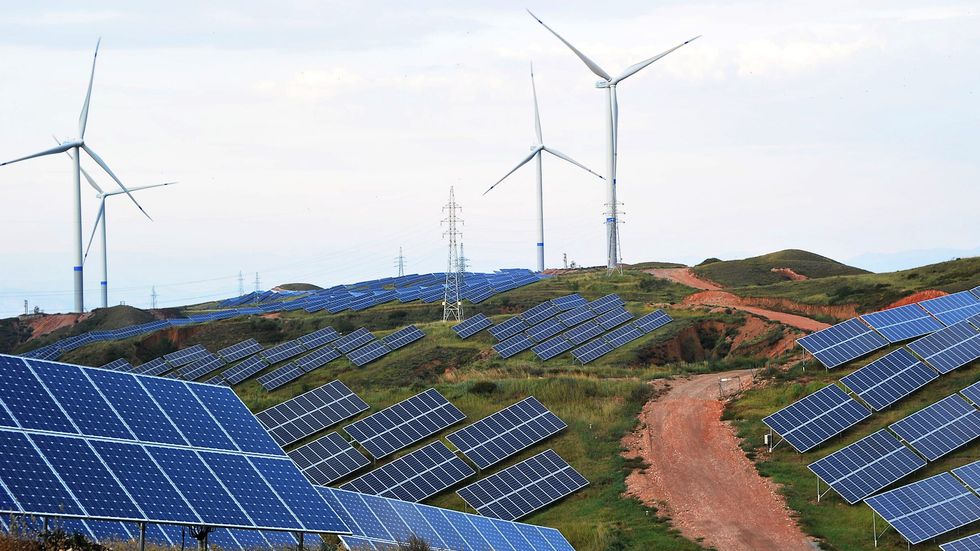 Solar panels and wind turbines are pictured on a mountain at Shenjing Village on July 2, 2018, in Zhangjiakou, China (photo by VCG).