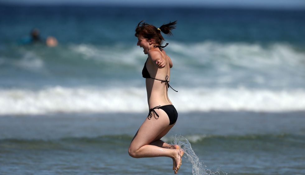 A woman jumps in the sea as the Boardmasters pro-surfing competition takes place on Fistral Beach on August 7, 2013 in Newquay, England. (Photo by Matt Cardy/Getty Images)