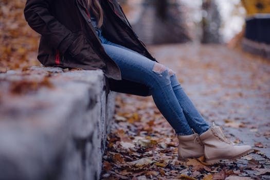 https://www.pexels.com/photo/woman-wearing-black-jacket-blue-distressed-jeans-and-brown-boots-sitting-on-gray-concrete-barrier-217860/