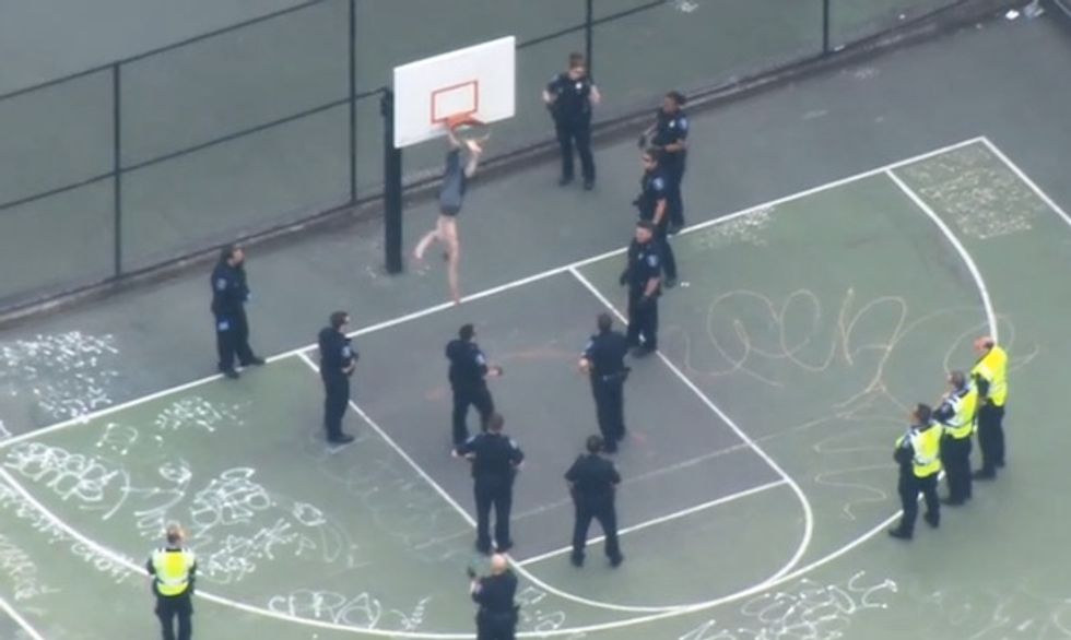 Shirtless, Hanging Upside Down, Swinging a Hammer at Police Possibly