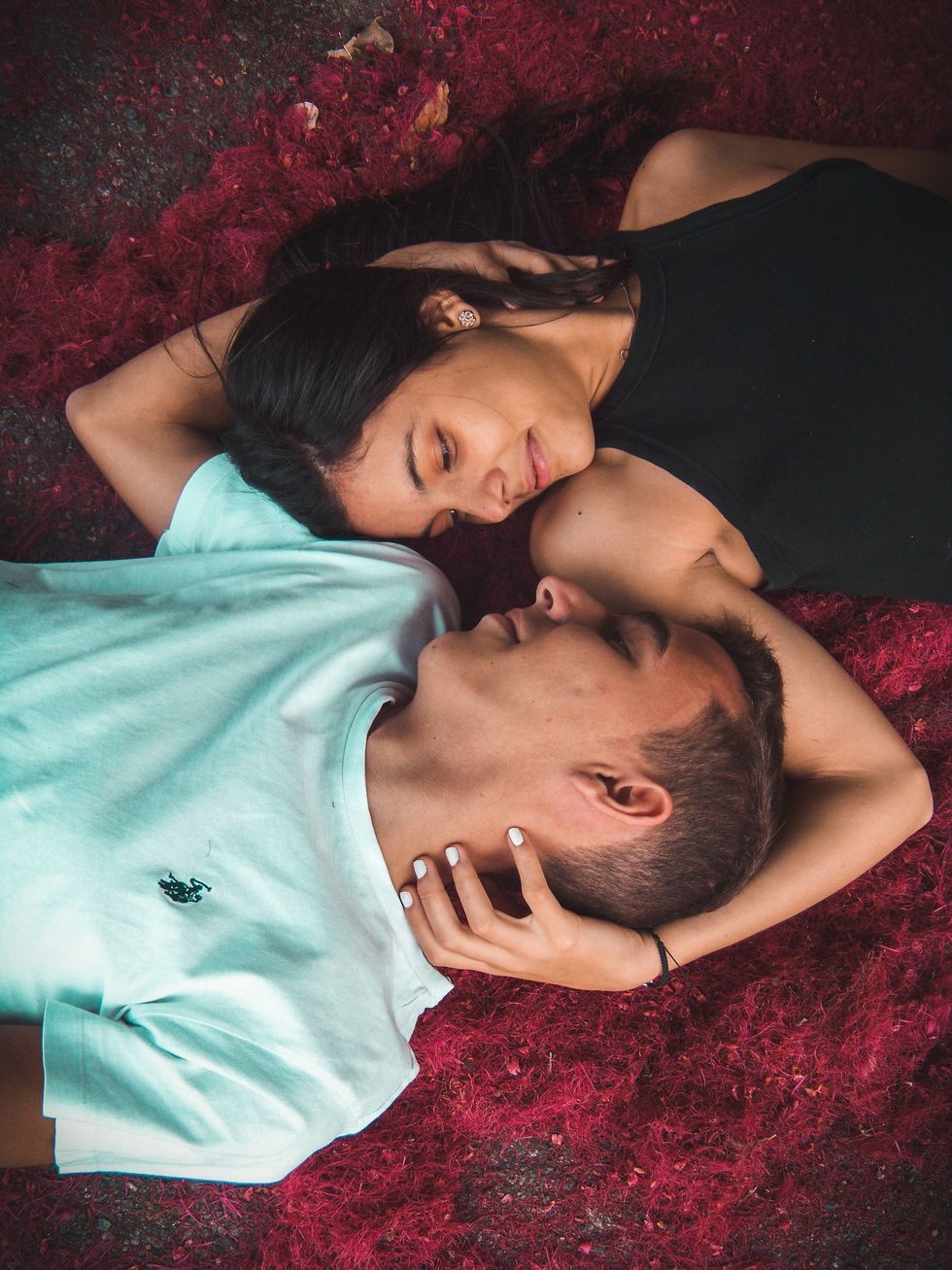 couple lying on ground looking at each other and smiling