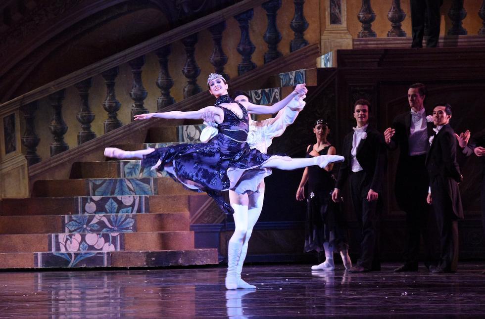 Dancer Jaimi Cullen leaps in a partnered grand jet\u00e9 in Nutcracker's party scene, wearing a black dress.