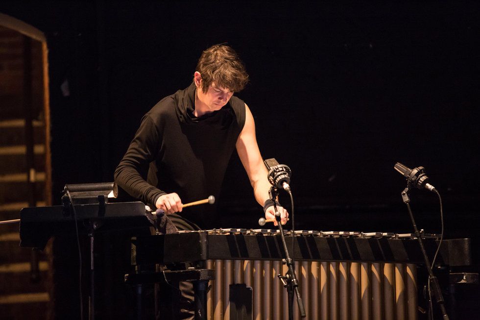 Drummer Glenn Kotche playing music on a dark stage