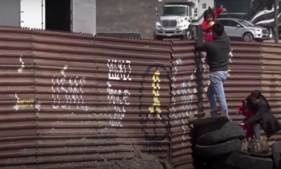 Toddlers passed over border fence into US as camera rolls — and