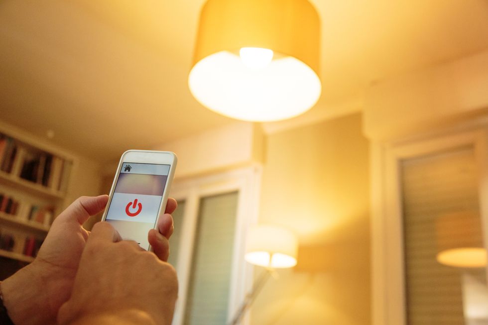a photo of a person turning on a smart light using his cell phone