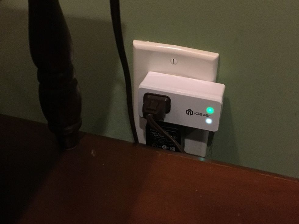 An iClever Smart Wi-Fi Mini Plug in an outlet with a white and green light on its front