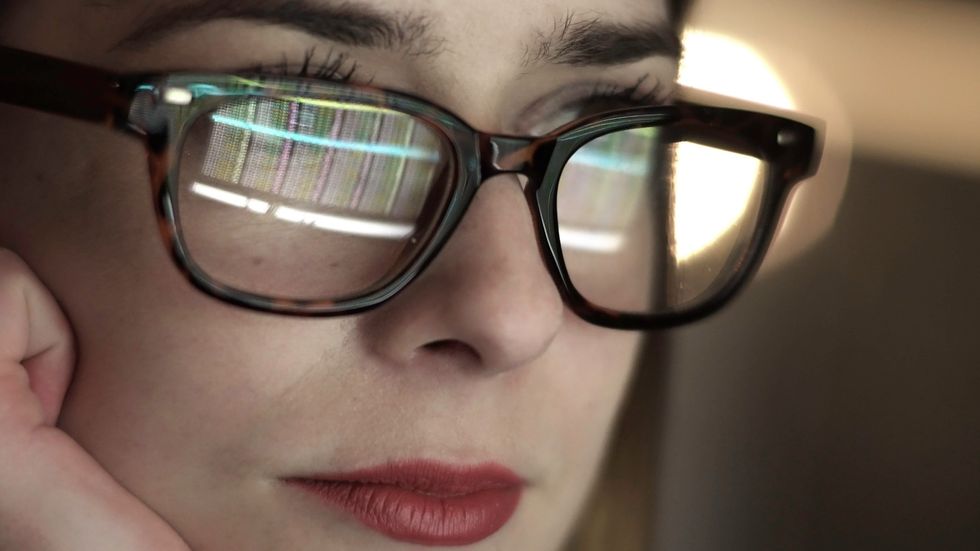 a woman wearing glasses looking at a computer screen