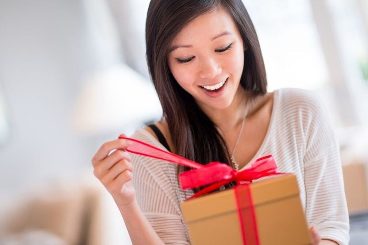 woman in white shirt opening gift with smile