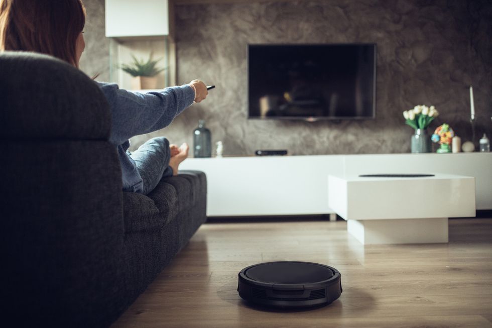 A photo of someone watching TV with a robot vacuum nearby, which we'll be able to control with our voice, even if we don't have it connected to the internet