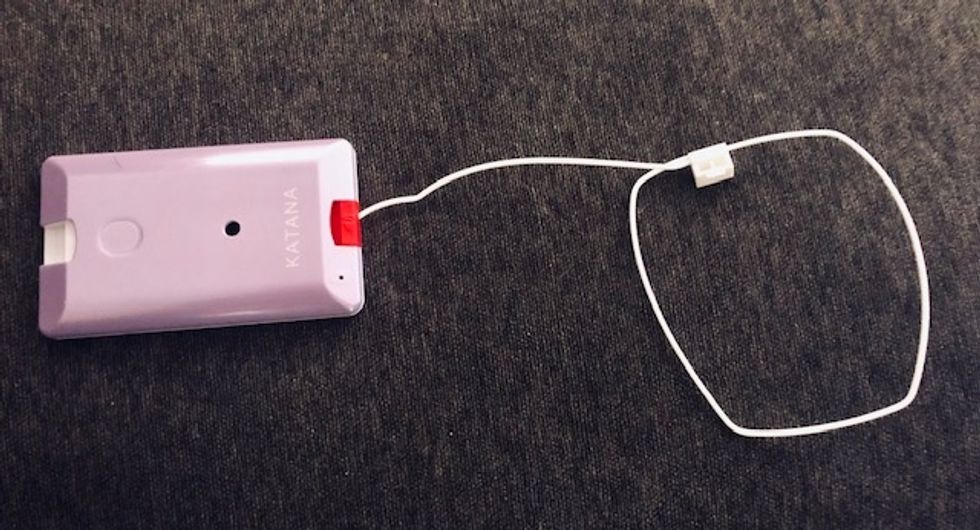 A photo of the Katana Arc which can be worn around your wrist, so when it drops, the red tab is pulled, sounding the alarm