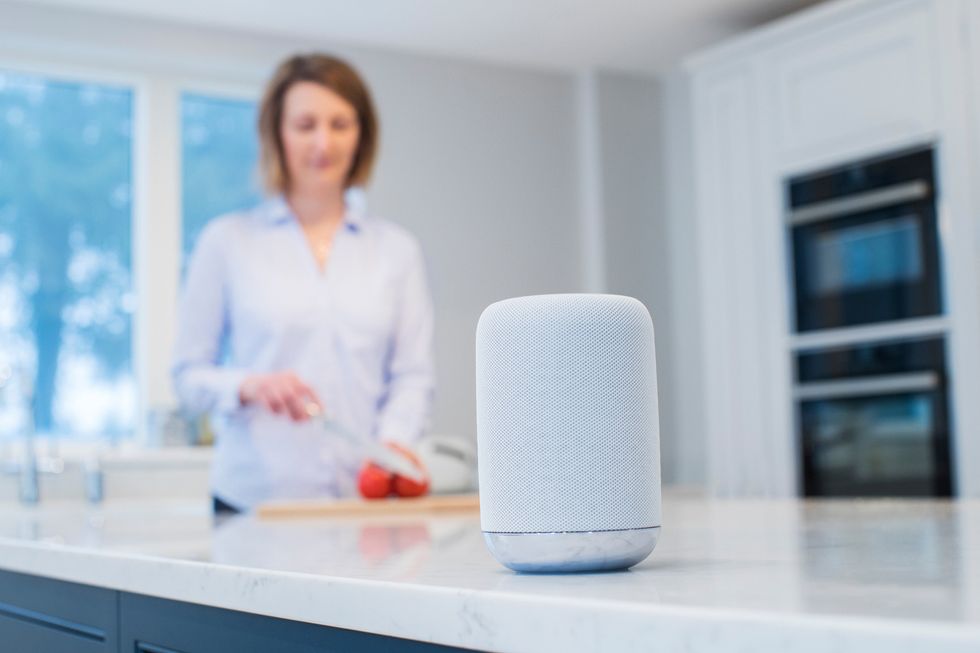 A photo of a woman, cooking in a kitchen with a smart speaker, which are expected to get more conversational in coming months