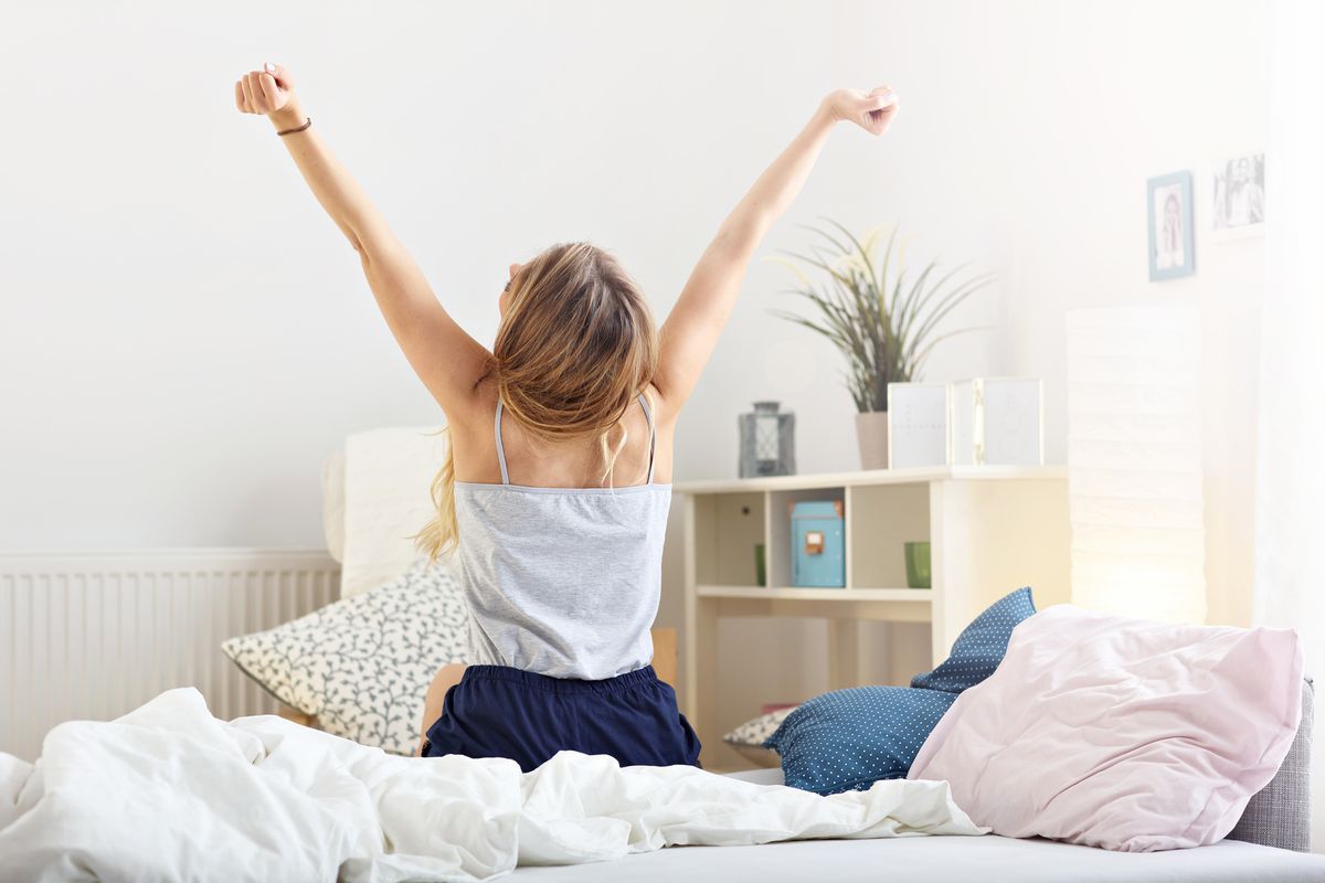 blonde woman stretching and getting out of bed
