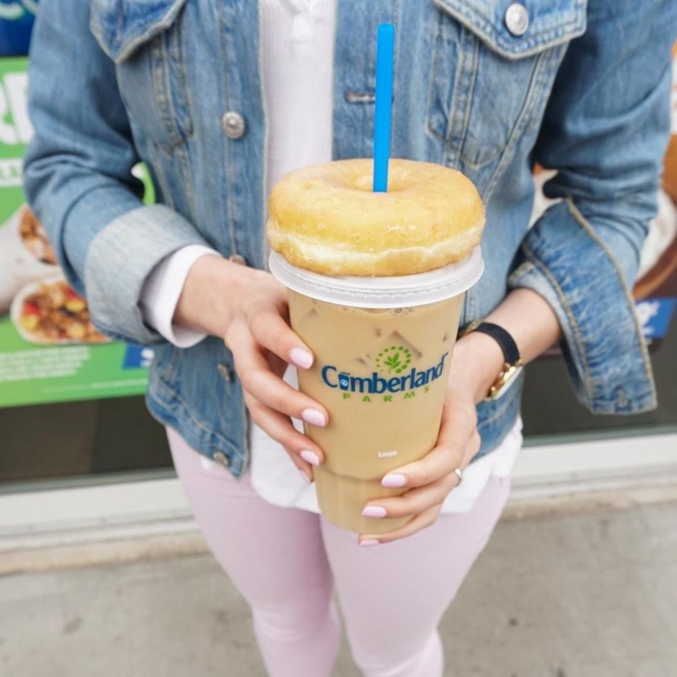 woman in denim jacket holding cumberland farms iced coffee