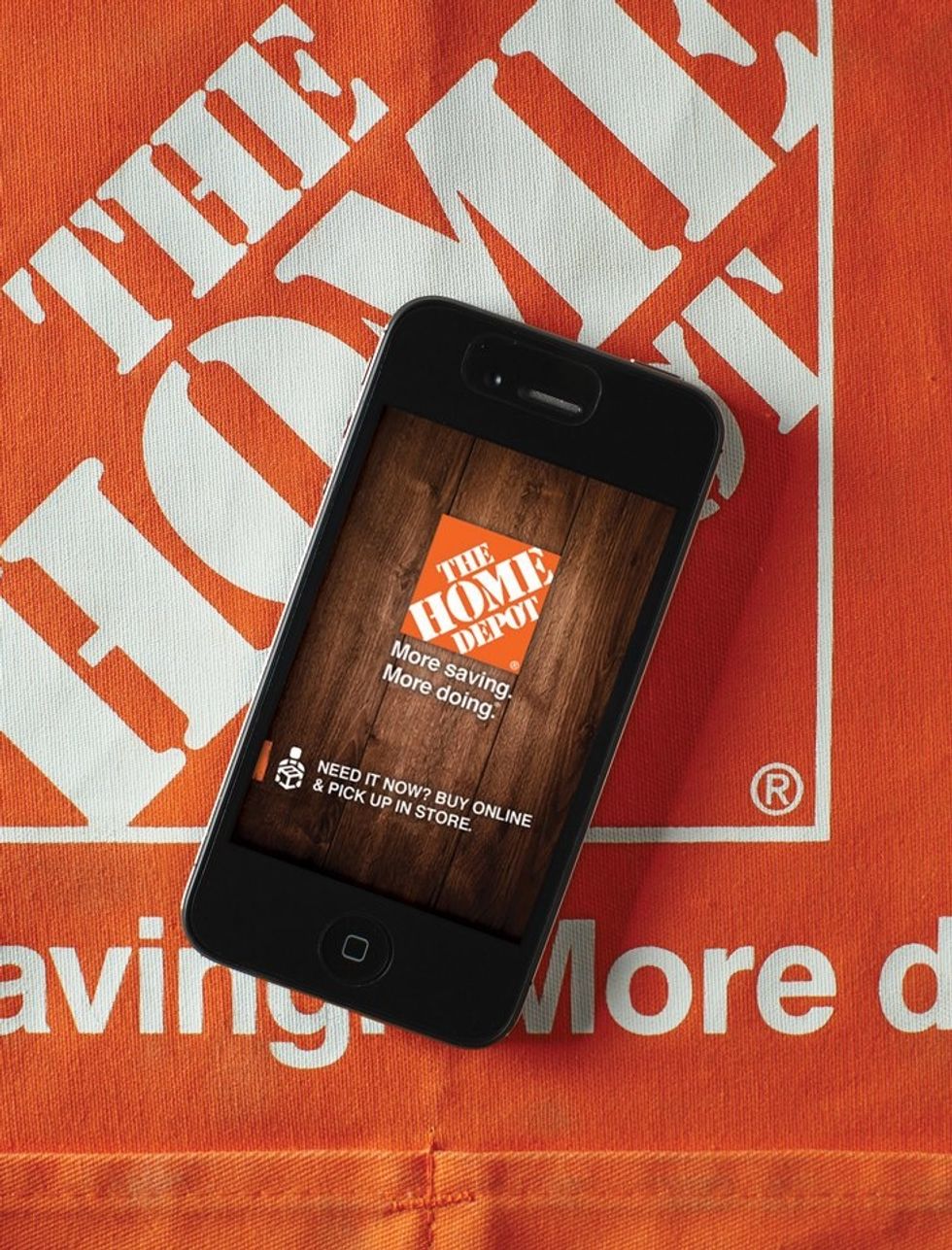 A photo of The Home Depot logo, and a smartphone showing online sales at the store, where you can \u200bbuy smart appliances, lighting and home security devices 