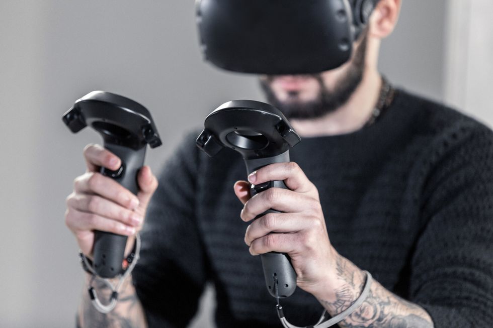 A photo of someone wearing a VR headset and holding two gaming controllers in their hands