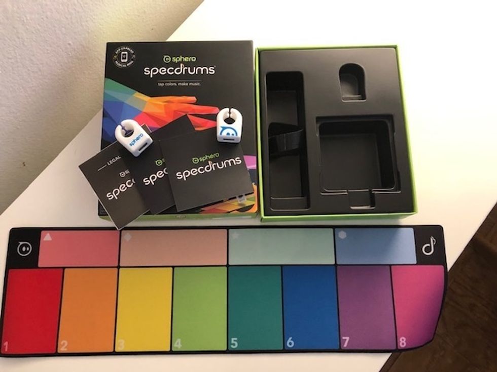 A photo of what you get inside the Sphero Specdrums kit, which includes a USB charge cord, a keyboard mat, and one or two rings