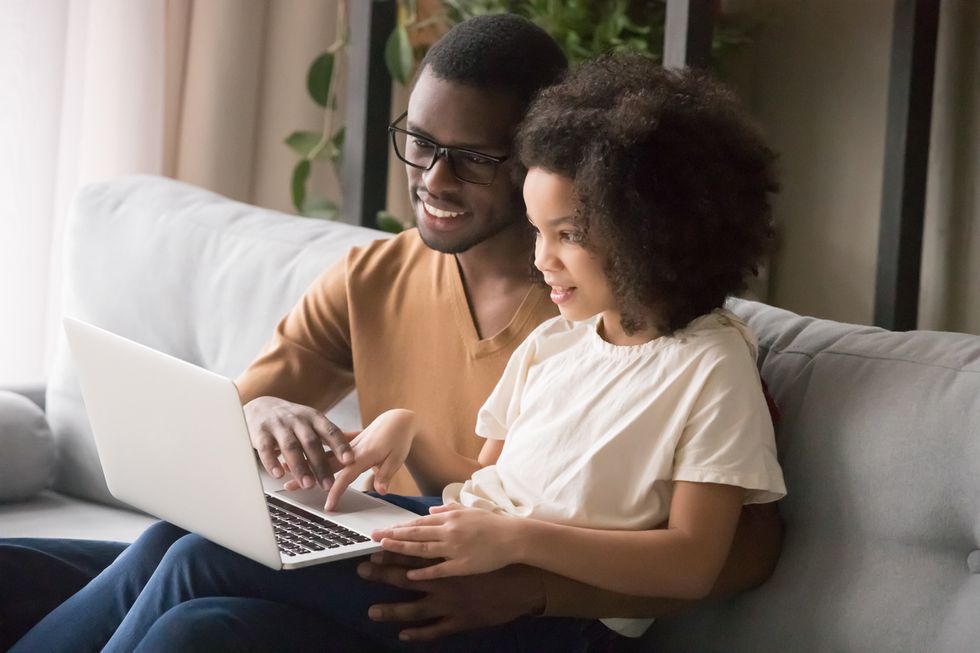 A photo of a parent and his child talking about online safety while holding a tablet