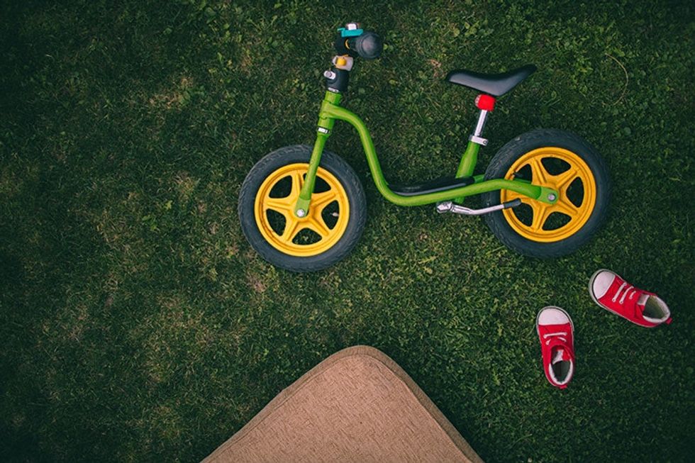 green and yellow bike lying in grass beside red shoes