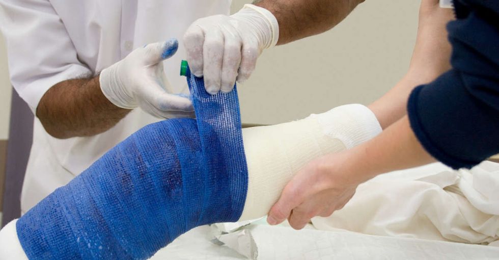 doctor wraps leg in cast with bandages