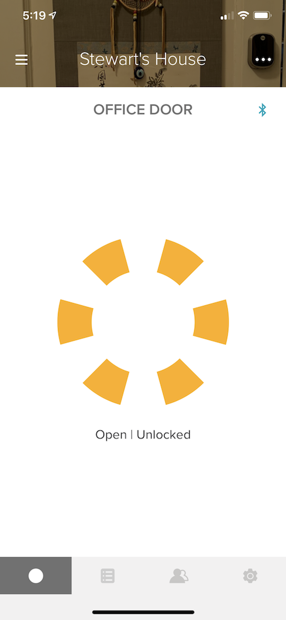 A photo of the app showing the Yale Assure Lock SL status as unlocked with a yellow pinwheel 
