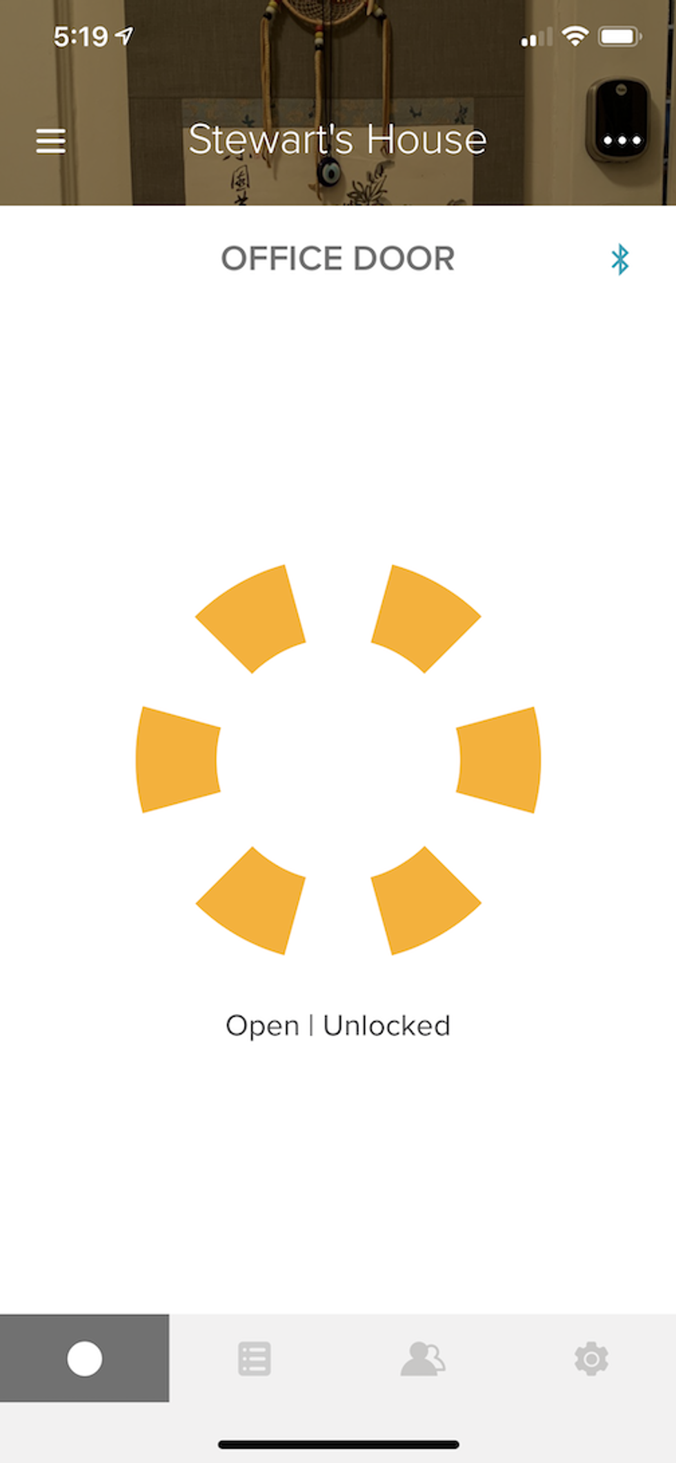 A photo of the app showing the Yale Assure Lock SL status as unlocked with a yellow pinwheel