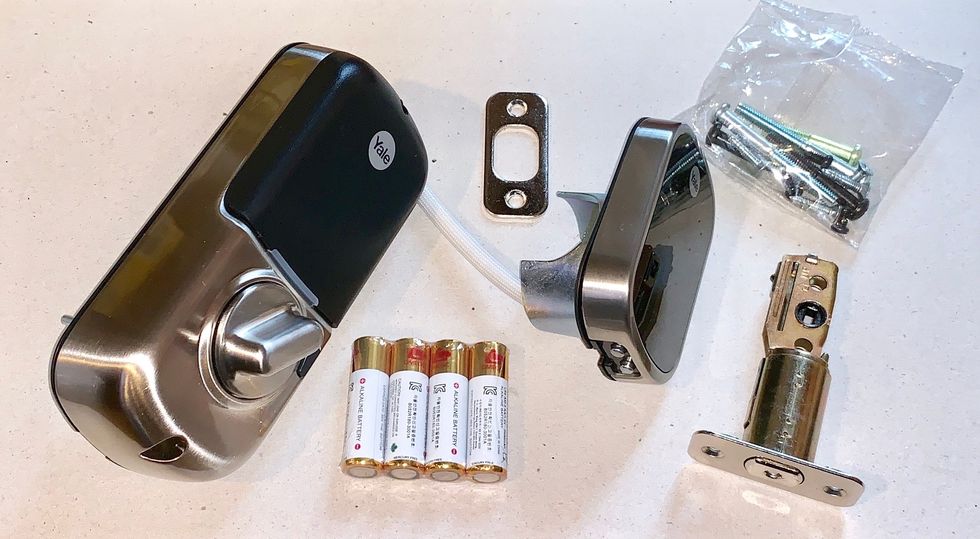 A photo of everything that will come with the Yale Assure Lock, including batteries and screws