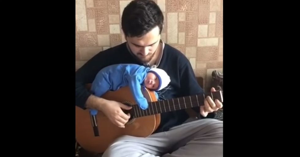 This chill dad serenading his baby to sleep while it rests on top of his guitar is 2019's must-see concert.