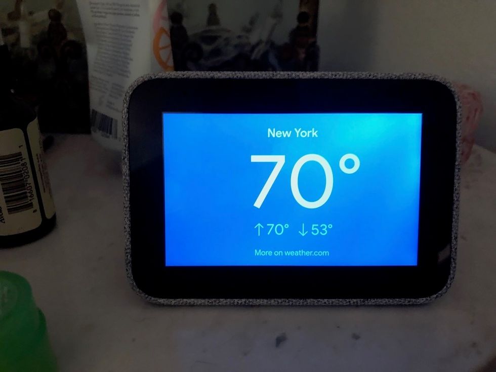 A photo of the Lenovo Smart Clock, rectangular shaped with a blue screen showing the temperature at 70 degrees and the words 'New York'