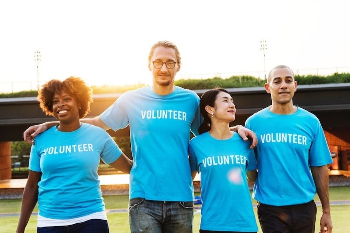 Four people in blue "Volunteer" shirts smiling outdoors.