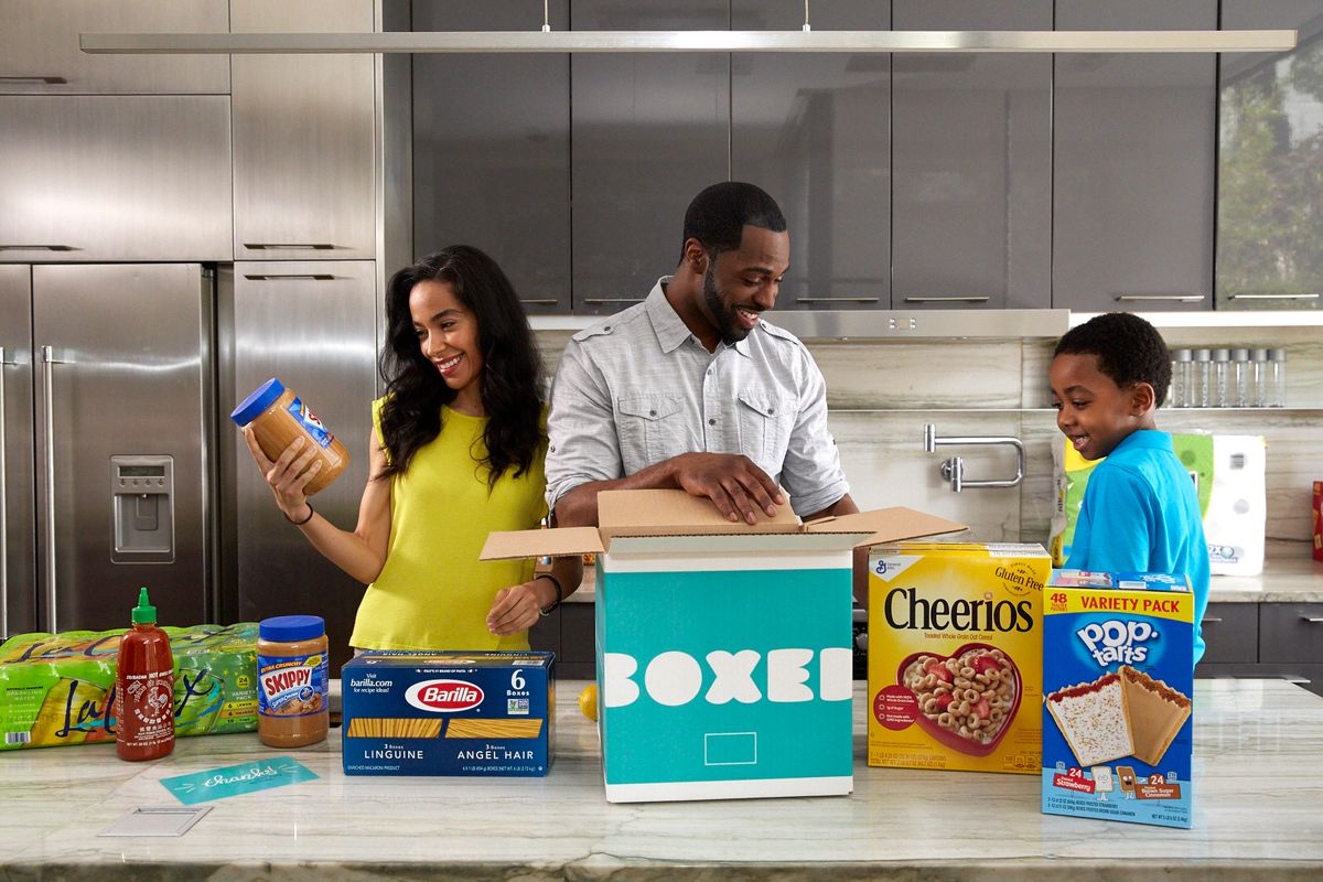 A family of 3 opens a box of food and snacks in their chrome kitchen