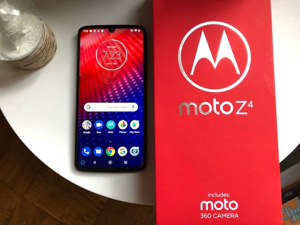 The Moto Z4 smartphone next to the red box, on a white table